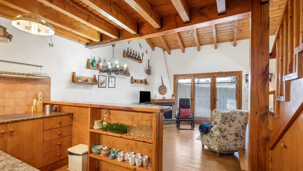 Un interior de madera con cocina, comedor y sala de estar con un sofá y una silla.