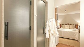 A hotel room with a bed, a robe hanging on the wall, and a door.