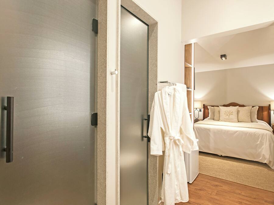 A hotel room with a bed, a robe hanging on the wall, and a door.