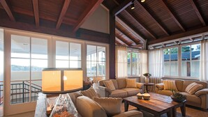 A spacious living room with a large window, a wooden ceiling, and a cozy seating area with a coffee table and cushions. - Varanda Boutique Hotel (Gramado)