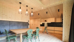 Una cocina moderna con armarios de madera, un comedor con mesa y sillas de madera, e iluminación colgante.