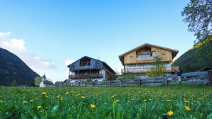 Una casa de madera con balcón y un campo de flores amarillas al frente.