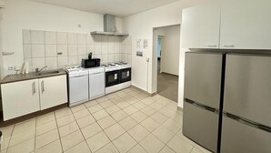 Eine Küche mit weißen Schränken, einem Herd, einer Spüle und einem Kühlschrank.