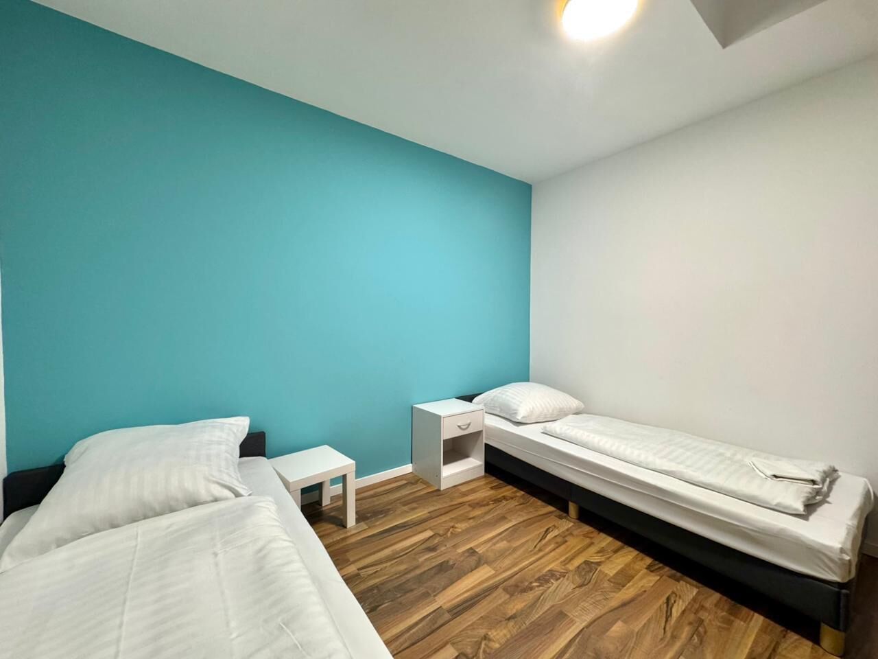 A room with two beds, a small bedside table, and a nightstand.