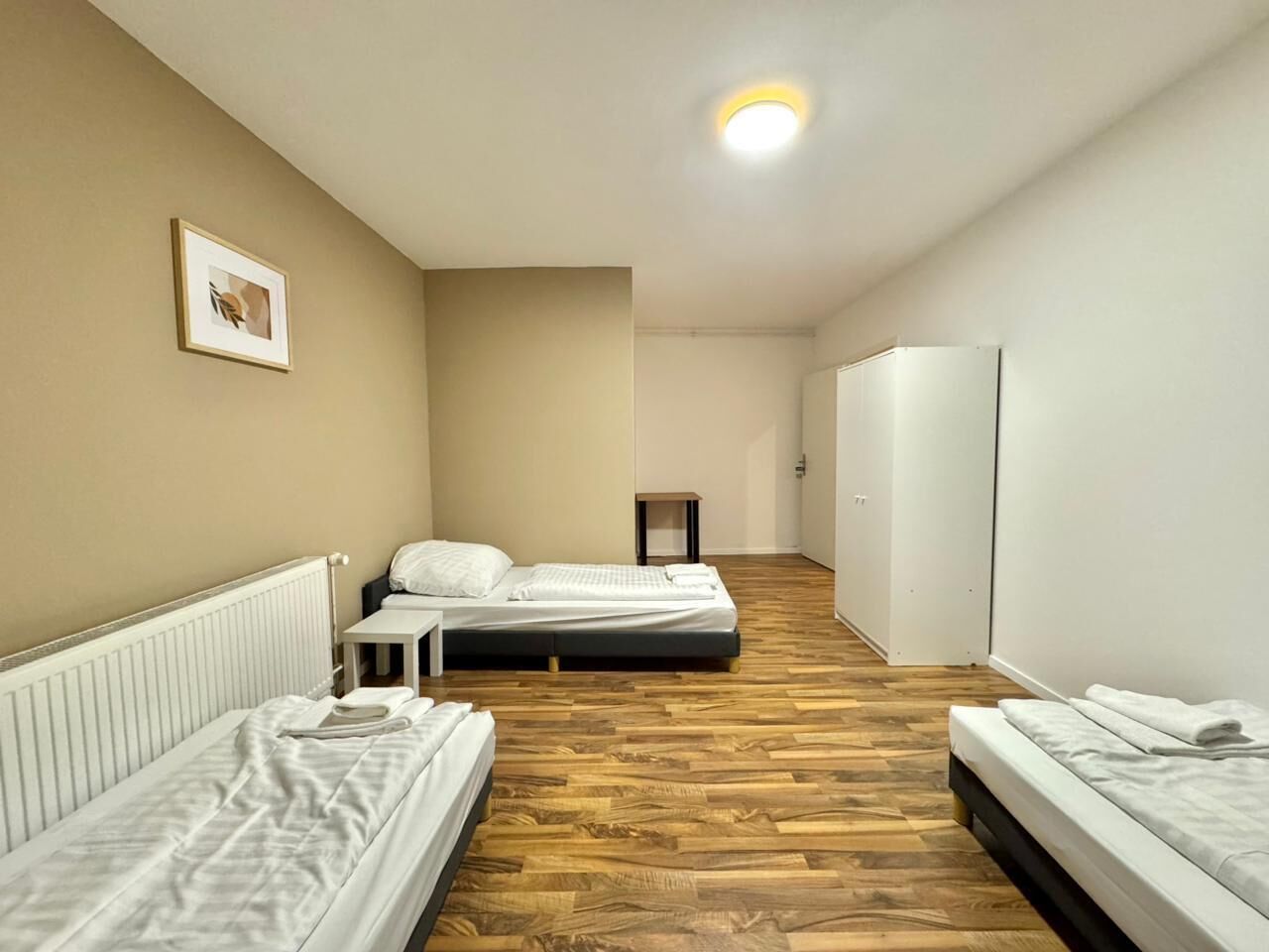 Hotellihuone, jossa on kaksi erillistä sänkyä, pieni pöytä, vaatekaappi ja patteri.