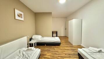 Hotellihuone, jossa on kaksi erillistä sänkyä, pieni pöytä, vaatekaappi ja patteri.