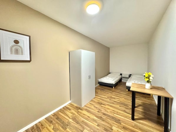 A compact room with a bed, a small table with a vase, a wardrobe, and a framed picture on the wall. - Casa Heusenstamm (Heusenstamm)