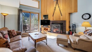 A living room with a fireplace, leather sofas, a wooden coffee table, and a television.