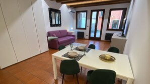A dining area with a white table, green chairs, and a purple sofa. - Veronetta 52 Garden - Verona Journeys (Verona)