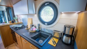 A compact kitchen with a sink, stove, and coffee maker.