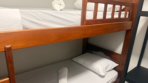 A bunk bed with white bedding and a rolled towel on the lower bunk. - Comfort at HC UFU: Private Room, Wi-Fi, AC, Minibar, Full Kitchen (Uberlândia)