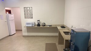 A compact kitchen with a refrigerator, microwave, coffee maker, and a water dispenser. - Comfort at HC UFU: Private Room, Wi-Fi, AC, Minibar, Full Kitchen (Uberlândia)