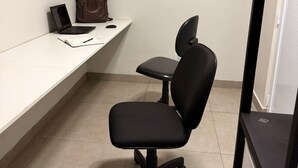 A small office space with a desk, a black office chair, a laptop, and a brown bag. - Comfort at HC UFU: Private Room, Wi-Fi, AC, Minibar, Full Kitchen (Uberlândia)