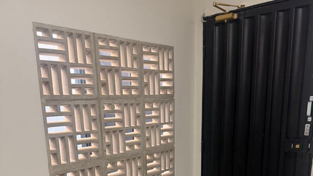 A hallway with a decorative wall panel and a black door with a handle. - Comfort at HC UFU: Private Room, Wi-Fi, AC, Minibar, Full Kitchen (Uberlândia)