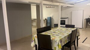 Un espace repas avec une table recouverte d’une nappe, entourée de chaises.