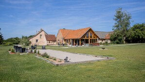Une grande maison avec une vaste pelouse, une véranda et un jardin bien entretenu.