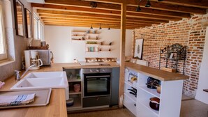 Une cuisine avec un plan de travail en bois, un évier, un four et un mur en briques.