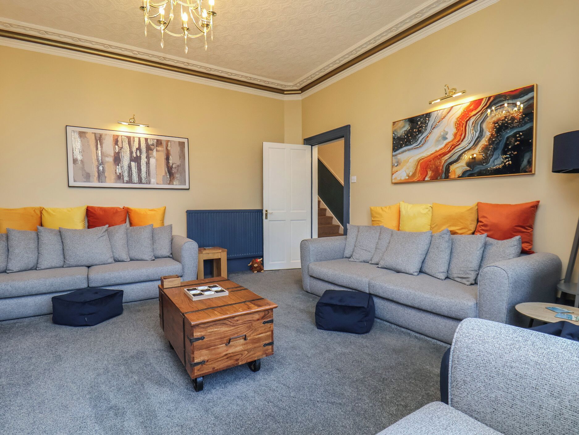 A living room with two grey sofas, colorful cushions, a wooden coffee table, and abstract art on the walls.