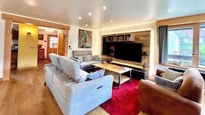 Ein modernes Wohnzimmer mit einem grauen Sofa, einem roten Teppich und einem flachbildfernseher, der an der Wand montiert ist.