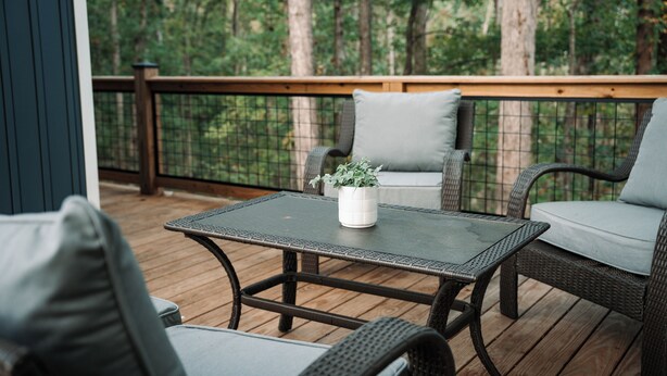Eine Terrasse im Freien mit Korbmöbeln, einem Tisch und einem Blumentopf.