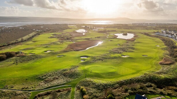 Luchtbeeld van een golfbaan met meerdere bunkers, waterhindernissen en een duidelijke speellijn.