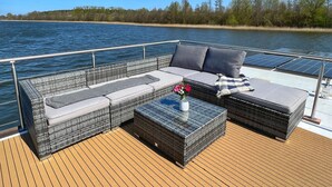 Una terraza con mobiliario de mimbre, una mesa de vidrio y paneles solares.