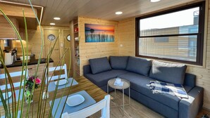 Interior acogedor de una caba ña con zona de comedor, sofá y un cuadro en la pared.