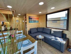 Interior acogedor de una cabaña con zona de comedor, sofá y un cuadro en la pared.