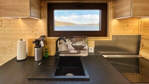 Una cocina moderna con televisor integrado, paredes de madera y un lavamanos negro.