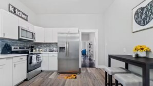 A modern kitchen with white cabinets, stainless steel appliances, and a wooden floor. - Petersburg Vacation Gem 3BR - Private Backyard (Petersburg)