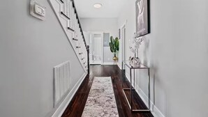 A modern hallway with a marble floor, white walls, and a staircase with a white railing. - Petersburg Vacation Gem 3BR - Private Backyard (Petersburg)