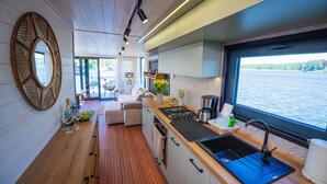 Een moderne keuken met een houten aanrecht, een zwarte spoelbak en een raam met uitzicht op een waterpartij.