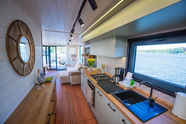 Une cuisine moderne avec un plan de travail en bois, un évier noir et une fenêtre donnant sur un plan d’eau.
