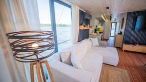 Een moderne kamer met een groot raam, een bed, een televisie en een houten vloer.