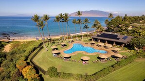 A resort with a swimming pool, palm trees, and a view of the ocean. - Ground-Floor Gem in Wailea Ekahi Village (Kihei)