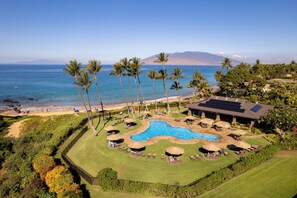 Ein Resort mit Swimmingpool, Palmen und Blick auf den Ozean.