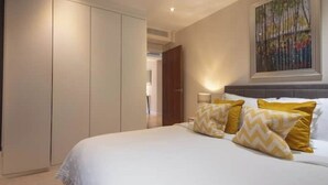 A bedroom with a bed, a wardrobe, and a painting on the wall. - Sunny Westminster 1-Bed with Terrace & AC – Walk to London’s Icons (London)
