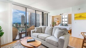 A modern hotel room with a balcony, a sofa, a small table, and a bed. - Chic Suite W/ Direct Ocean Views & Free Parking (Honolulu)