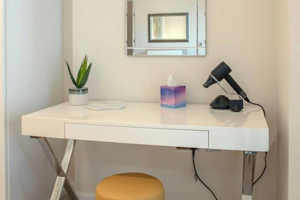 Un bureau blanc avec une plante en pot, une boîte de mouchoirs et un sèche-cheveux.