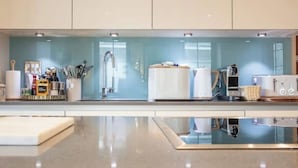 Una cocina moderna con salpicadero de vidrio, electrodomésticos de acero inoxidable y un diseño limpio y minimalista.