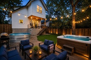 A backyard with a hot tub, outdoor seating, and a wooden deck. - Luxe 6BR Oasis | Pool•Hot Tub•Games | Near DTown (Austin)