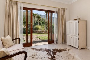 Ein Zimmer mit einer Schiebetür zum Garten, einem weißen Schrank und einem gestreiften Sofa.