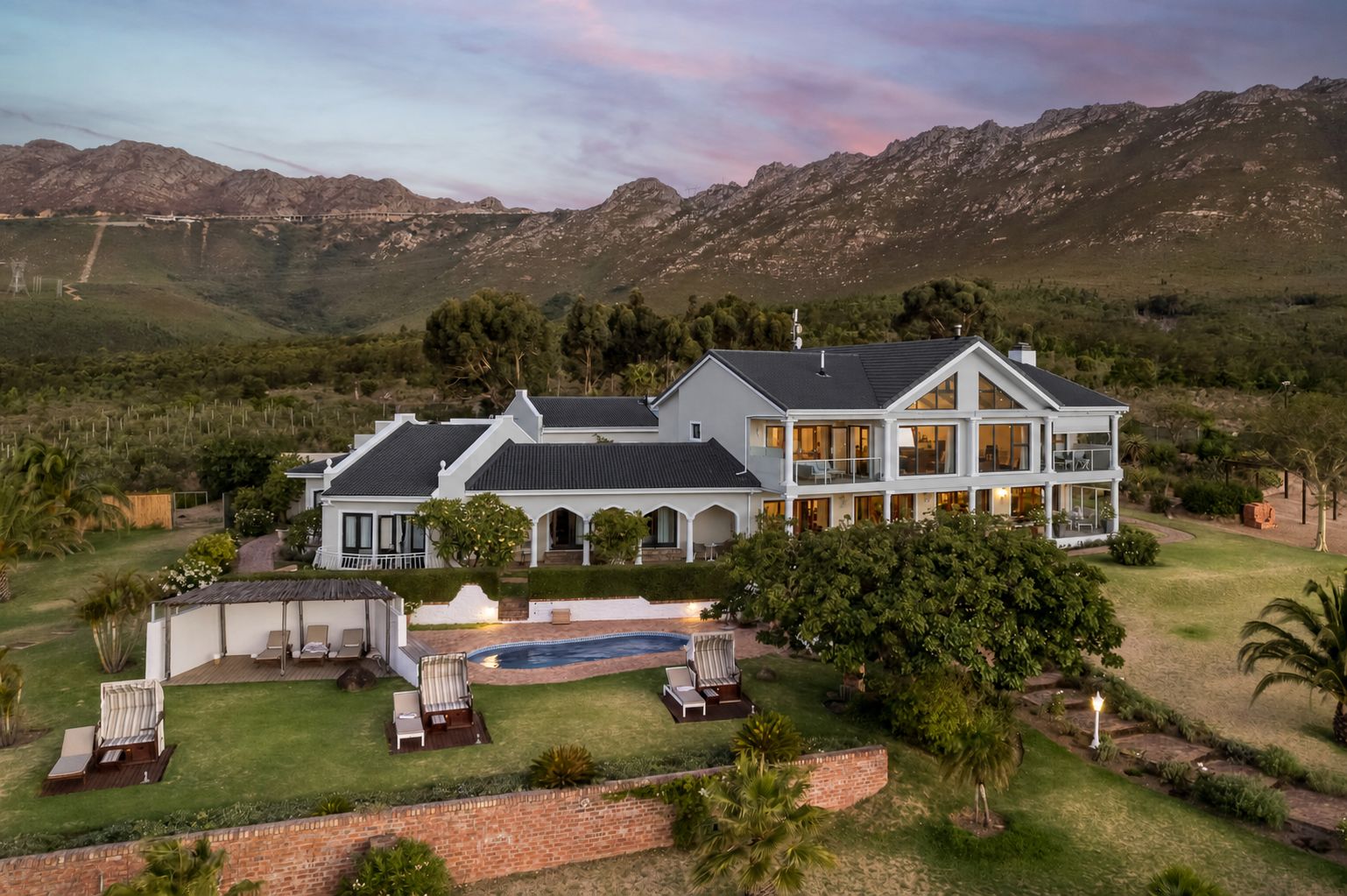 A large two-story house with a swimming pool, surrounded by a well-maintained lawn and trees.