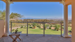Un balcone con vista su un giardino curato e montagne lontane.