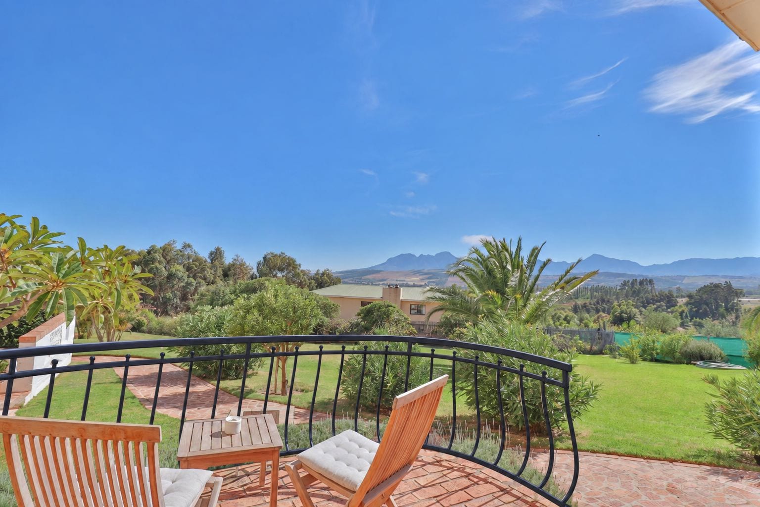 A balcony with a view of a mountainous landscape, a table, and two chairs.