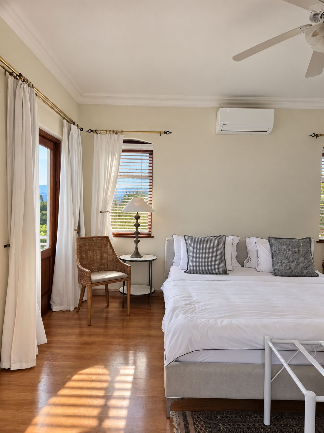 A bedroom with a bed, a chair, a table, and a window with curtains.