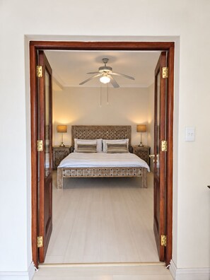 Ein Schlafzimmer mit einem Bett, einem Deckenventilator und zwei Nachttischlampen.