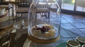 Un coin repas avec une table dressée pour un repas, agrémenté d’un centre de table en forme de dôme de verre contenant du fromage et des raisins.