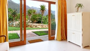 A room with a sliding glass door leading to a garden, a white cabinet, and a plant on a table.