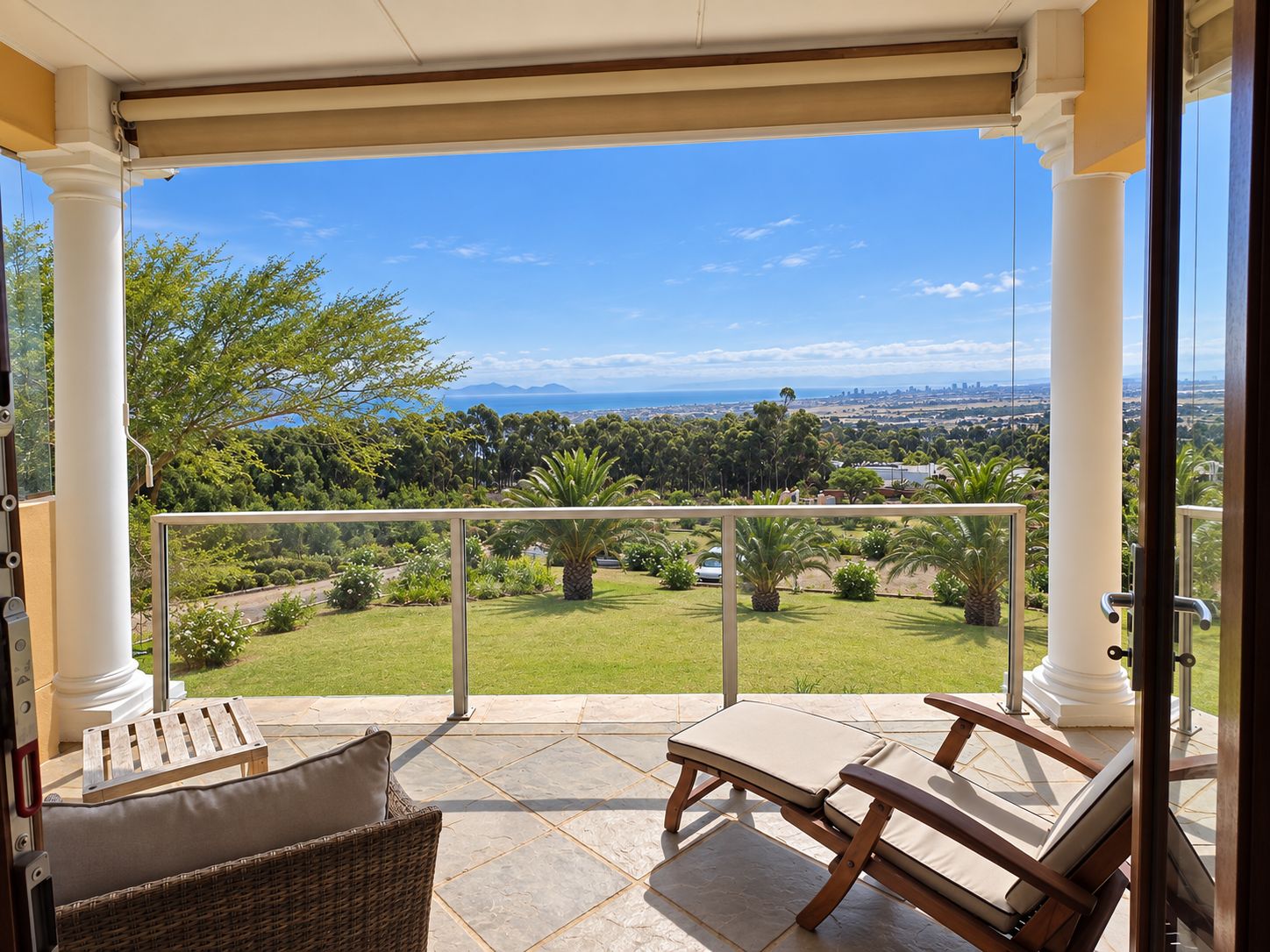 A balcony with a view of a green landscape and distant mountains.